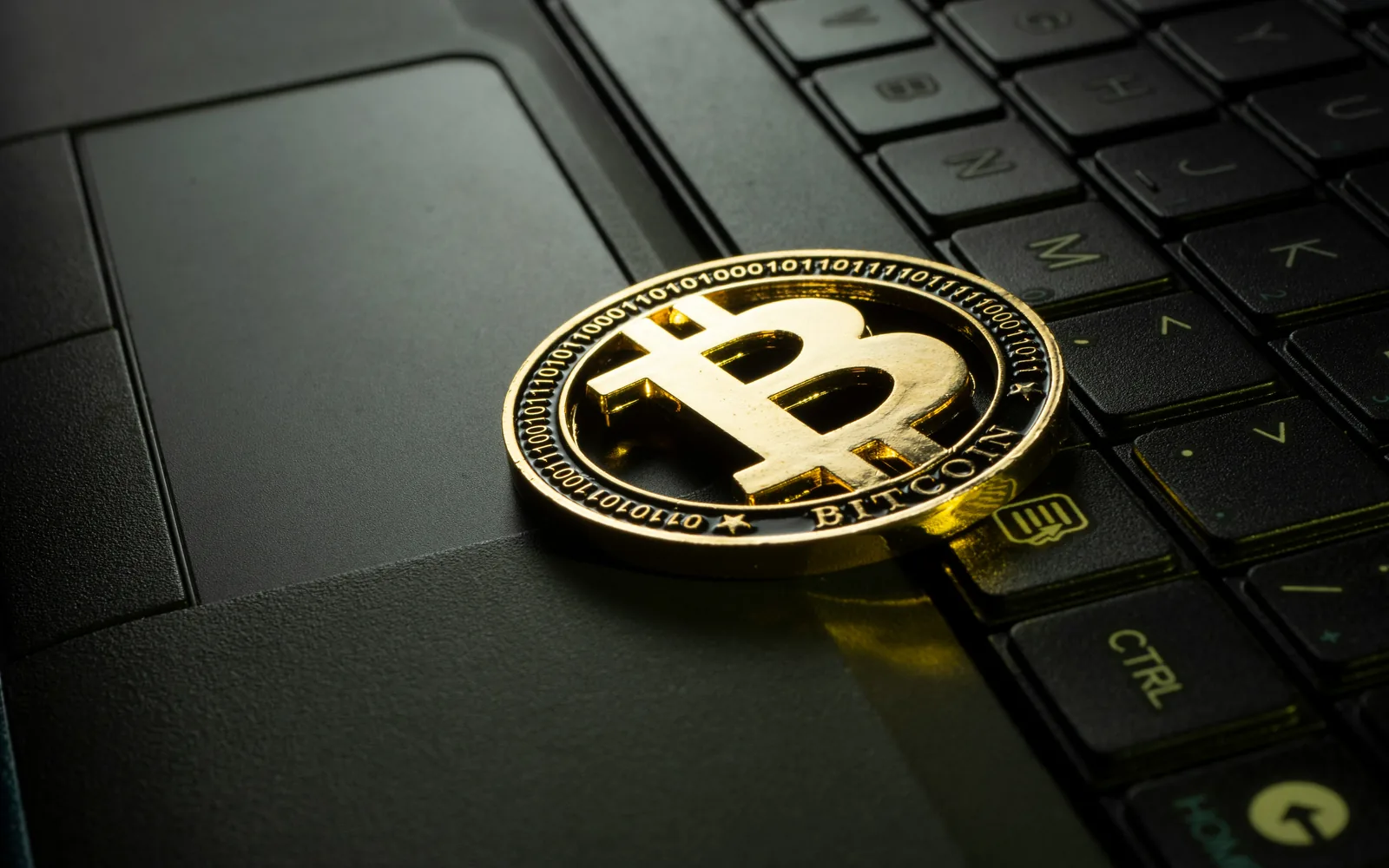 Gold bitcoin coin on a laptop keyboard