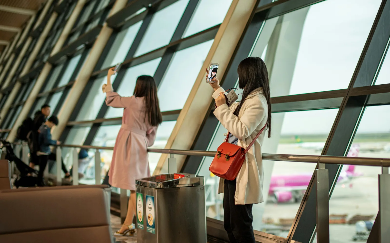 Two women taking selfies by airport window
