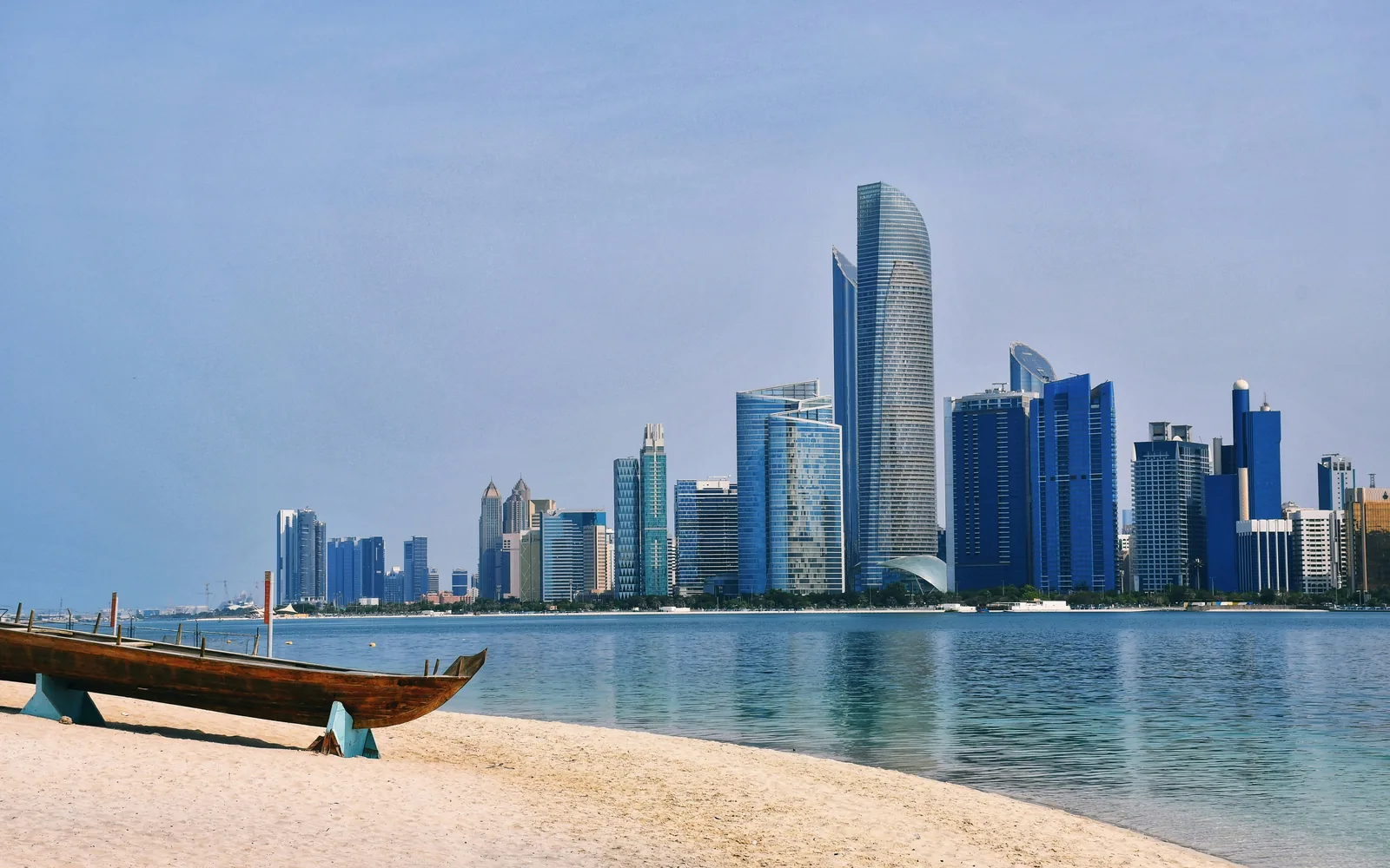 Abu Dhabi skyline from a beach with a wooden boat