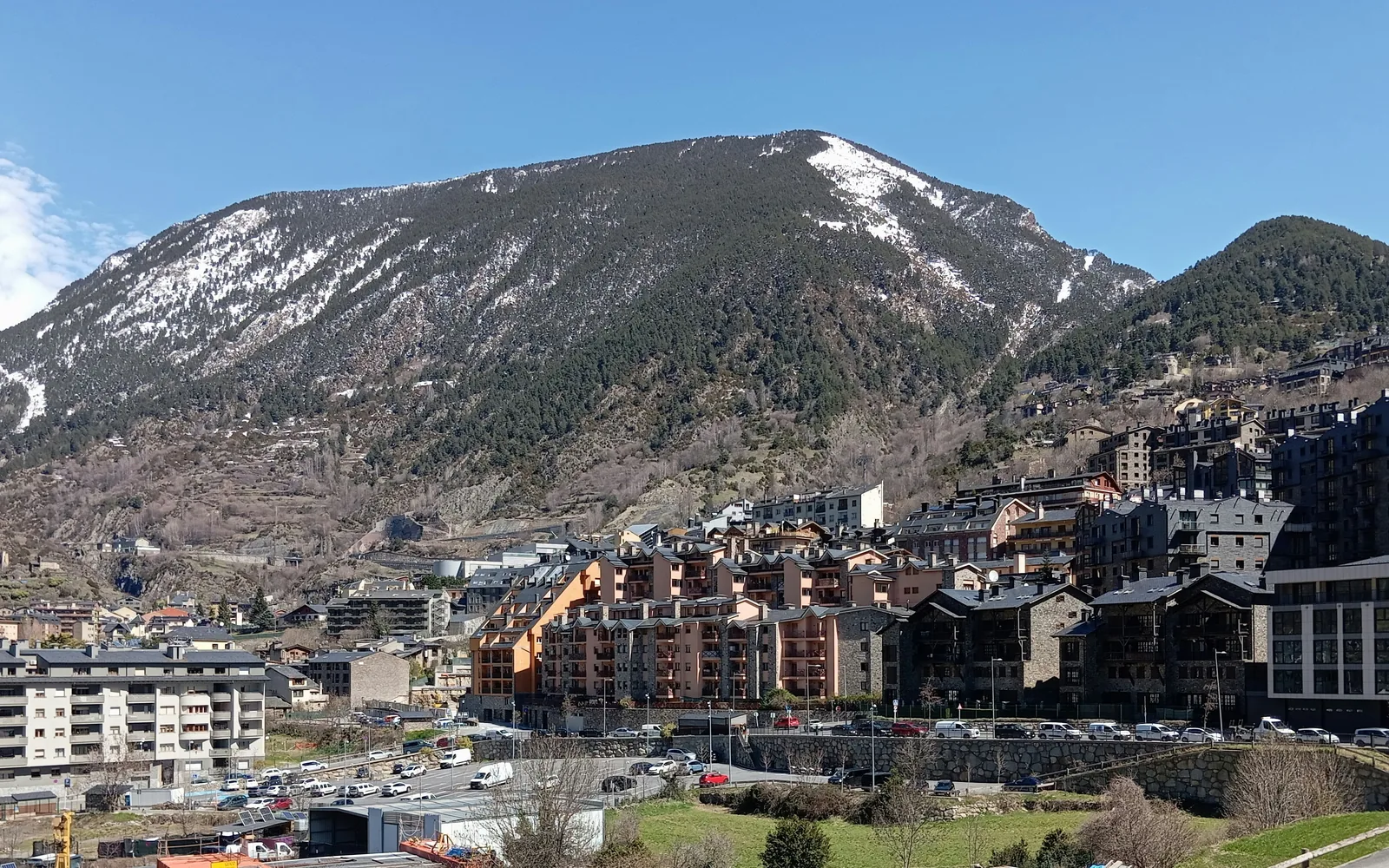 Snow-capped mountain overlooks a town with modern buildings.
