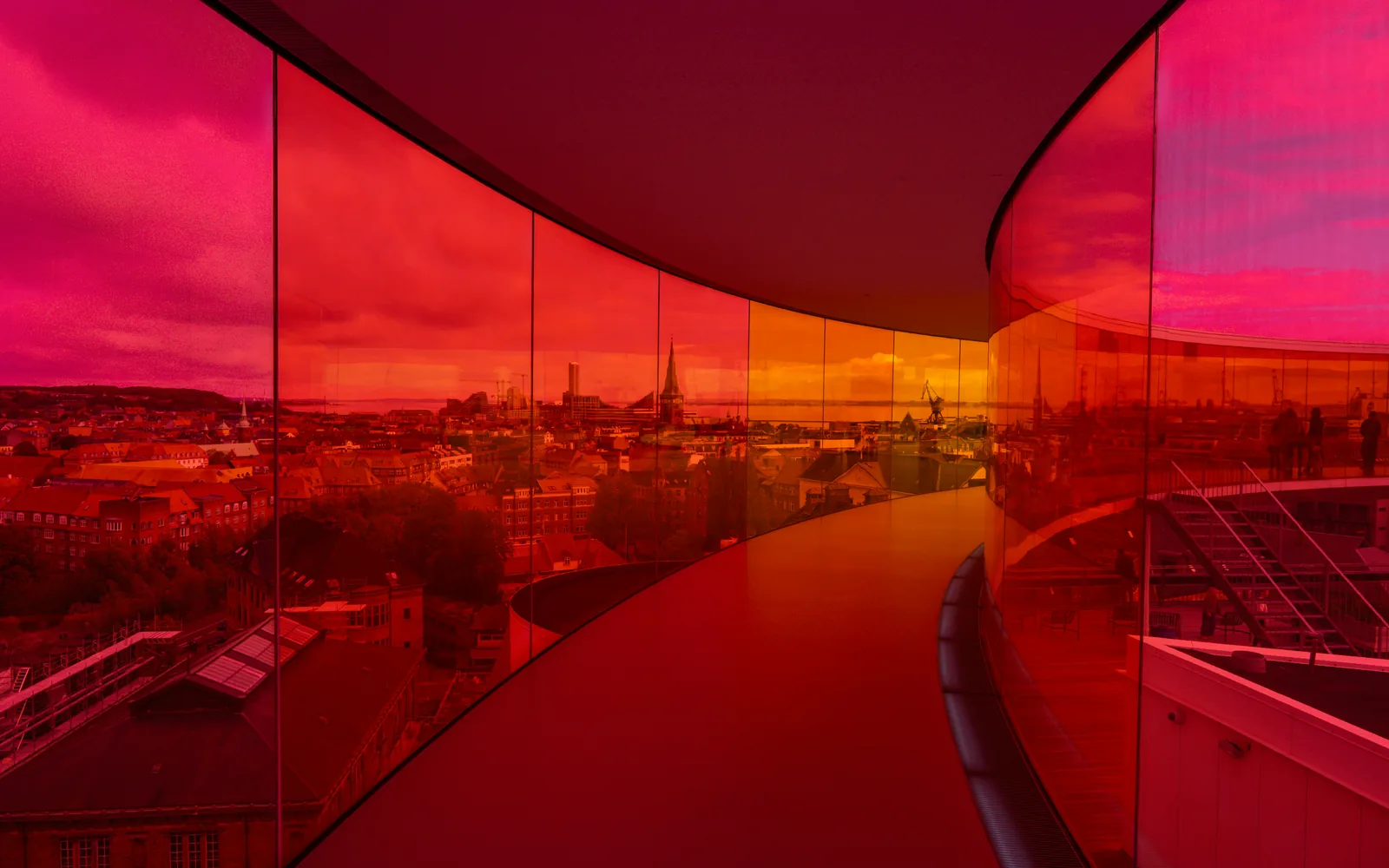 Modern architecture with colorful glass overlooking cityscape.