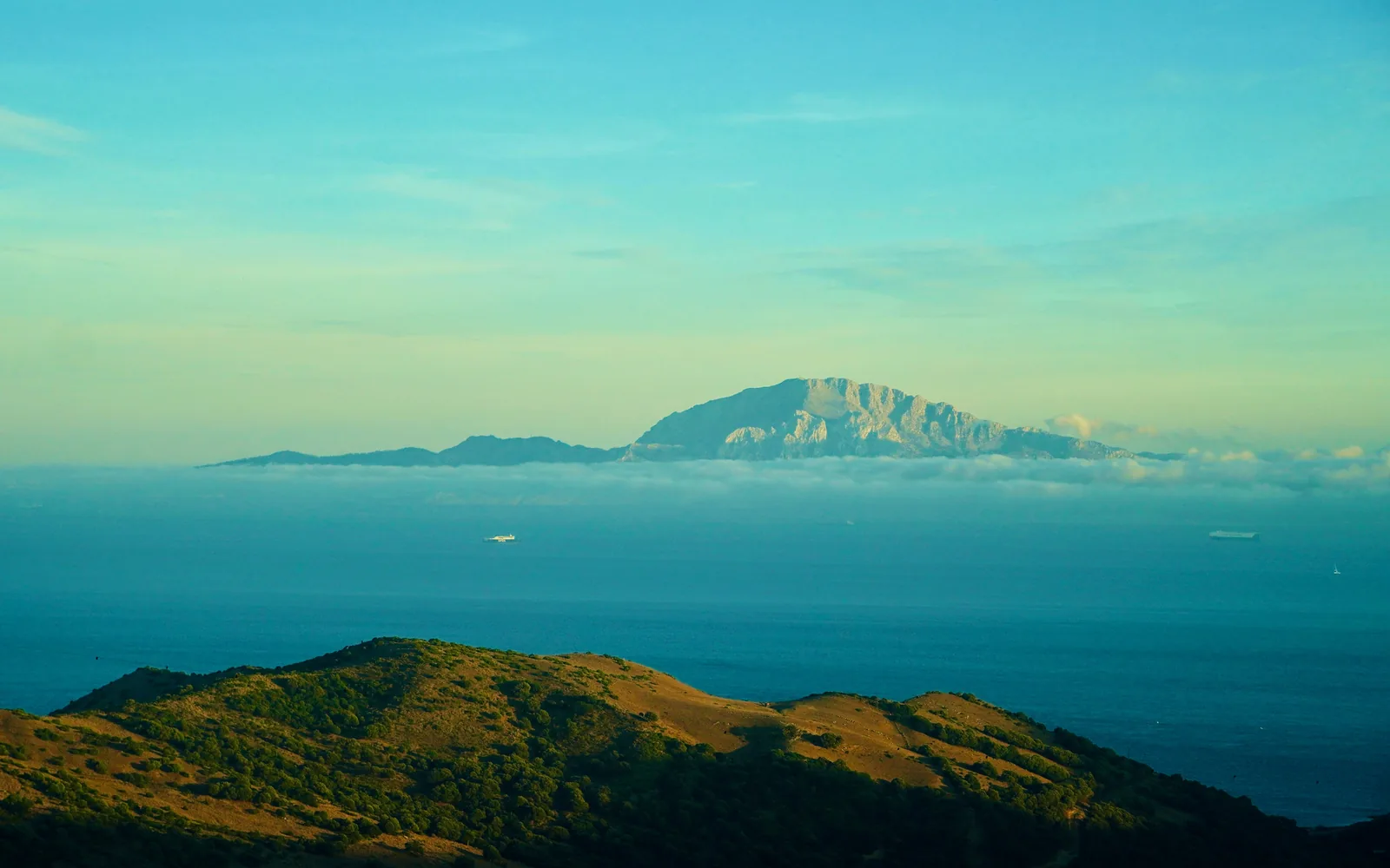 Distant mountain range across the ocean under sky