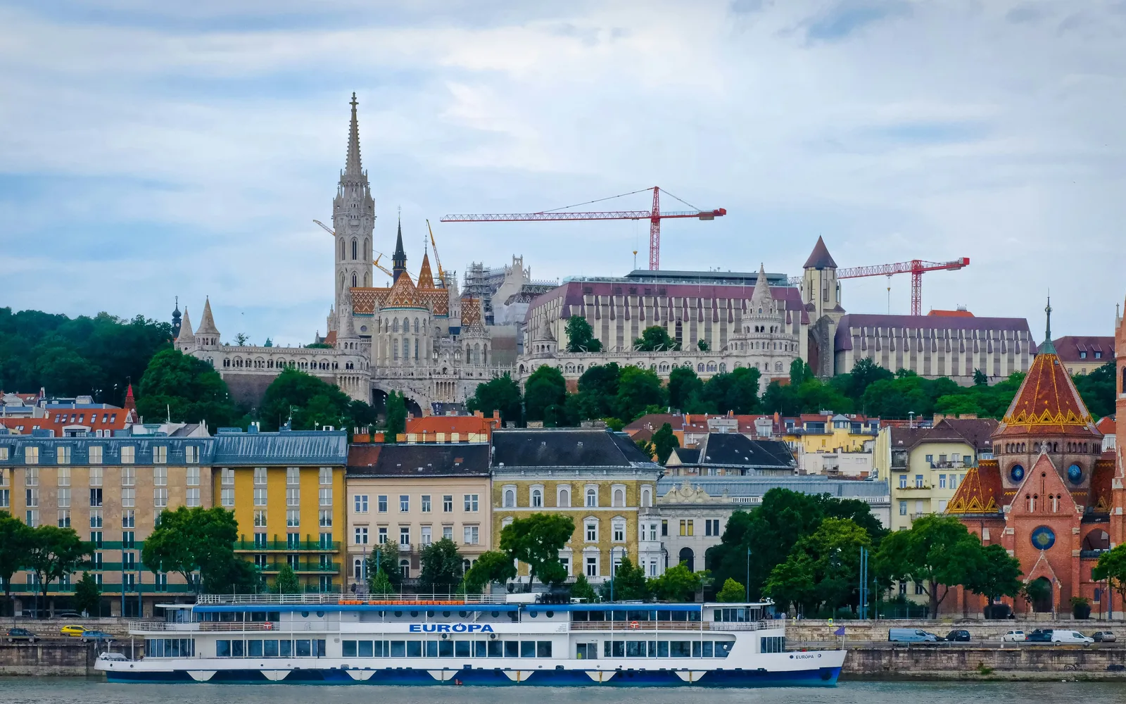 The breathtaking skyline of Budapest, featuring the Fisherman’s Bastion and Matthias Church perched on Buda Hill. These iconic landmarks offer panoramic views of the Danube River and the stunning cityscape of Hungary’s capital. The elegant river cruise ship in the foreground adds to the charm of this must-visit European destination.