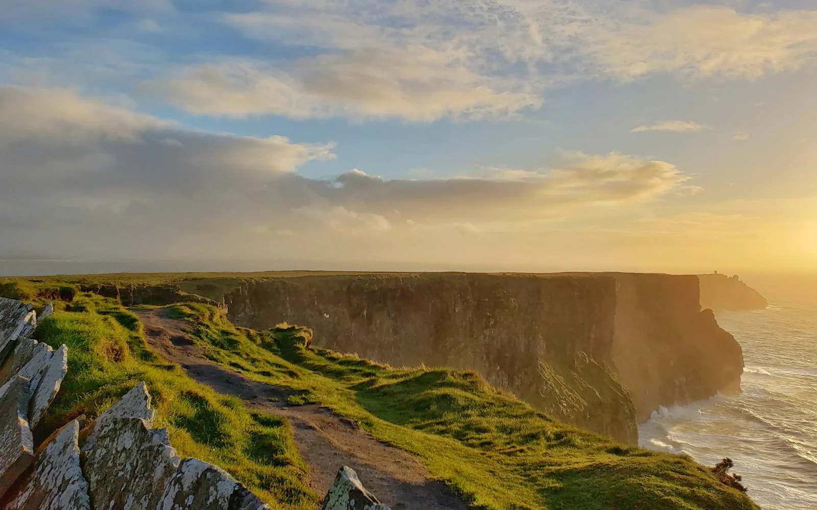 Green grass mountain under a cloudy sky at the Cliffs of Moher, Ireland