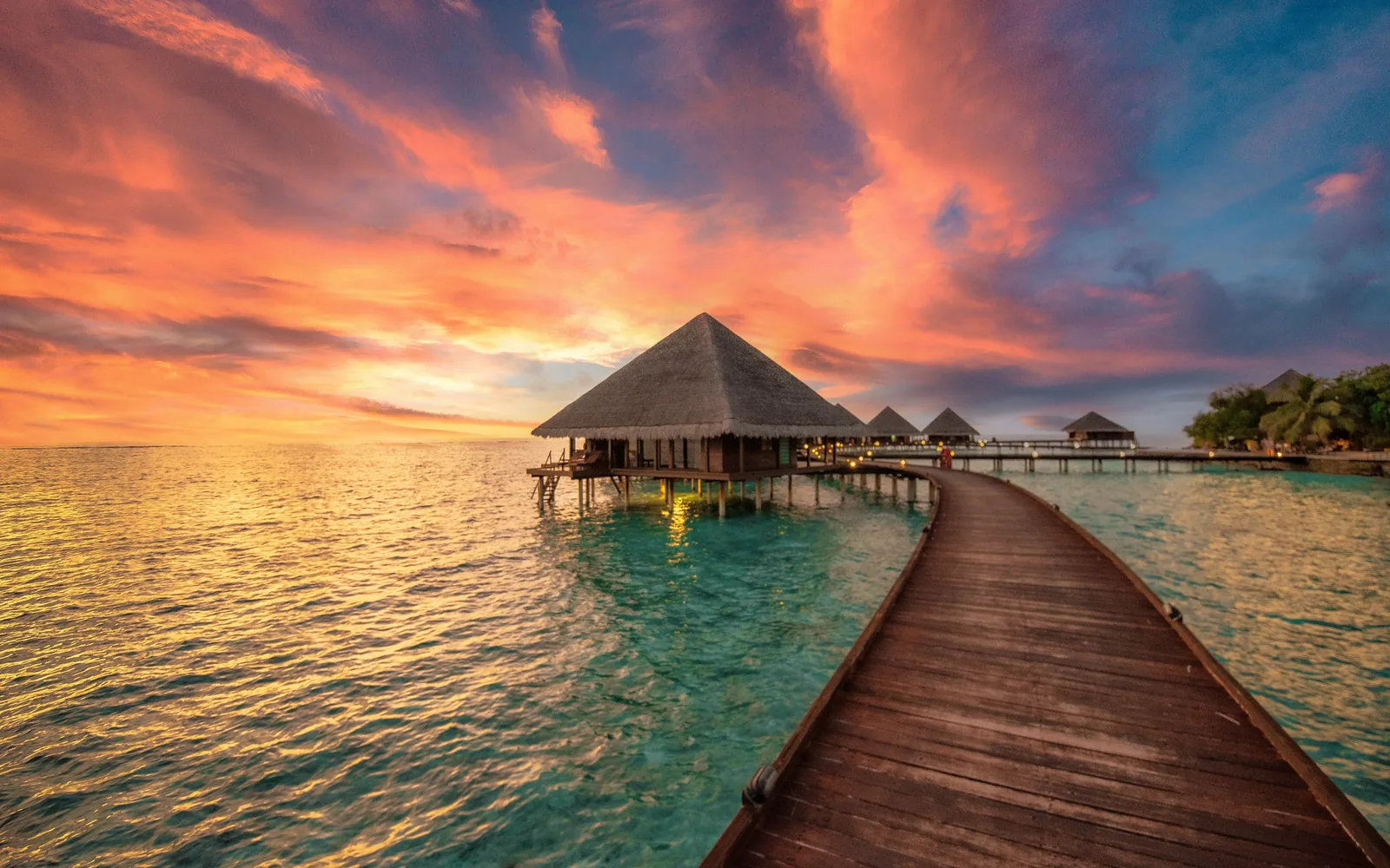 a dock leading to a hut in the ocean