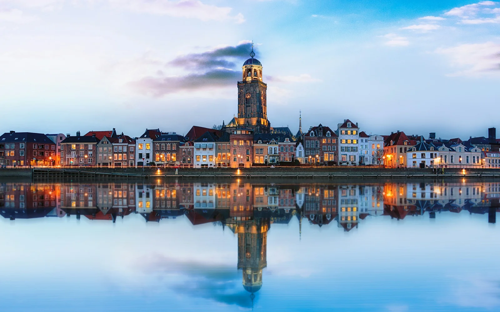 Lit-up Deventer skyline reflected on the river, Netherlands
