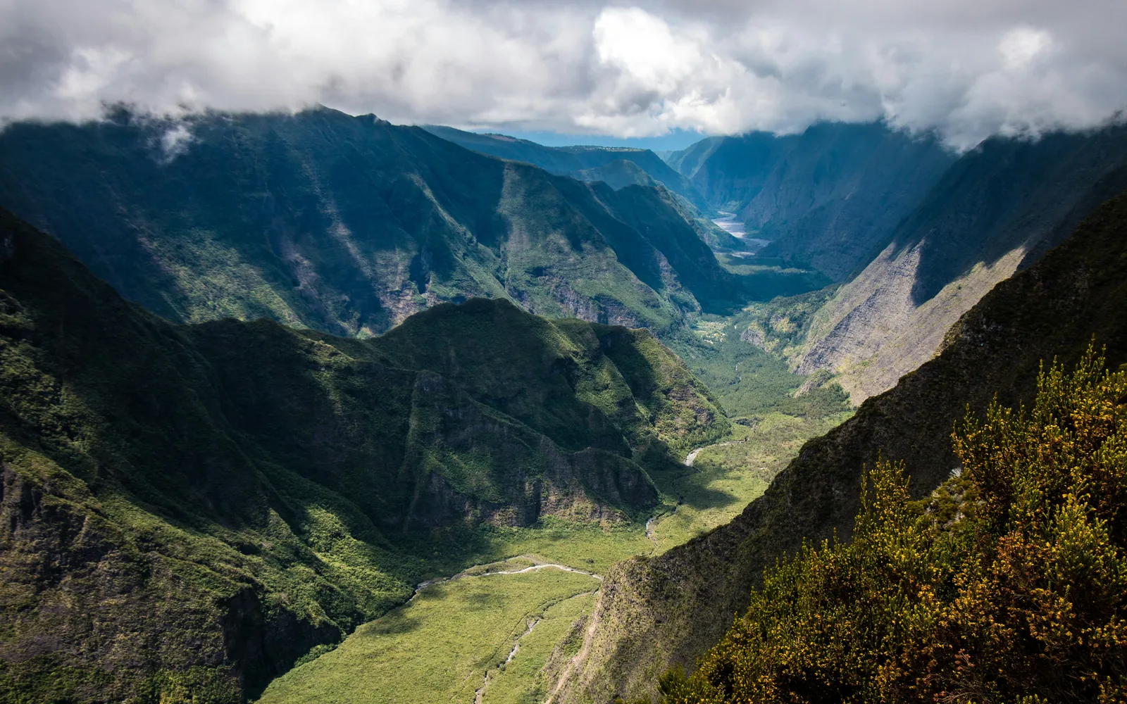 Green mountain valley below clouds near Piton de la Fournaise