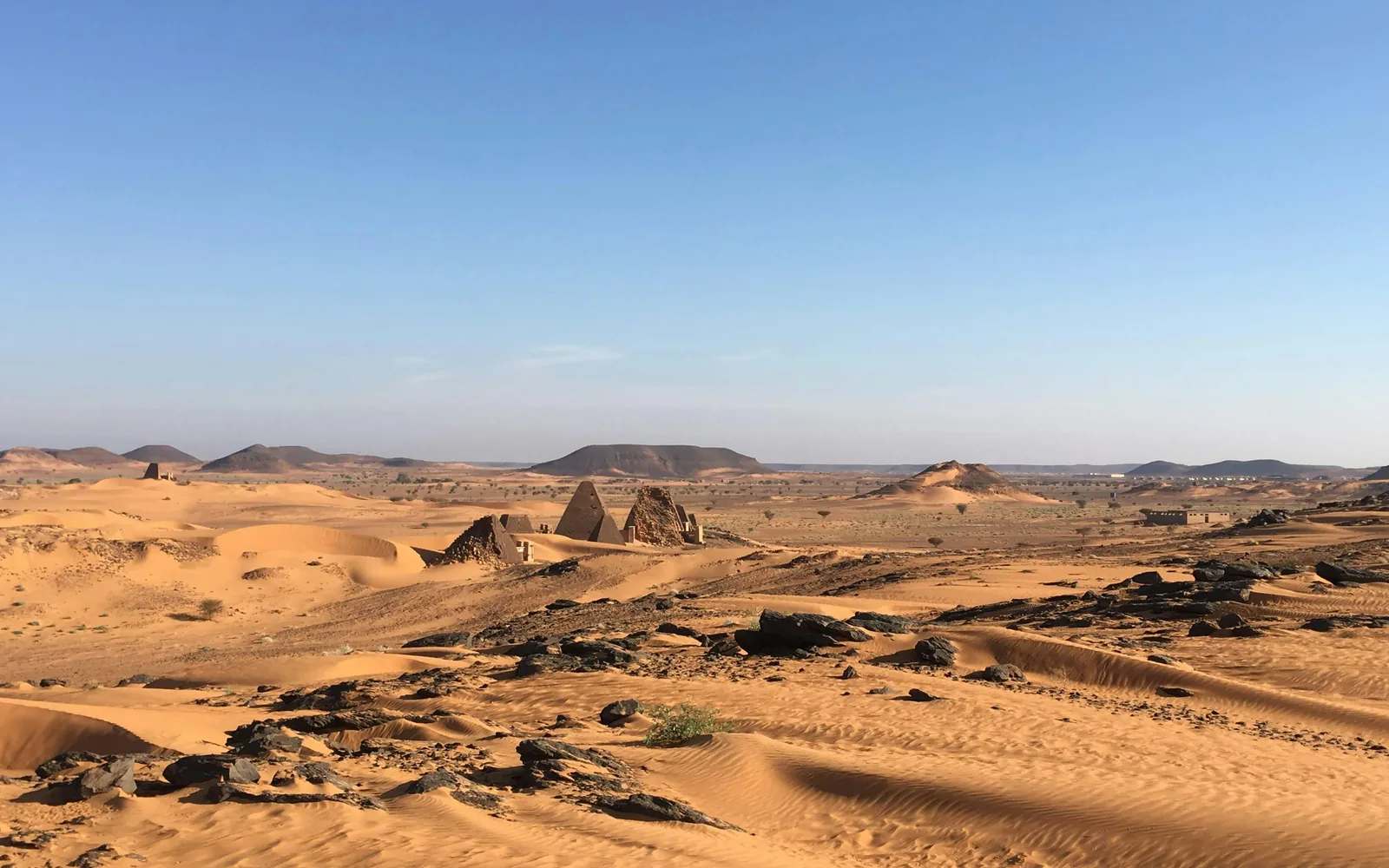 Ancient pyramids rise from a sandy desert landscape